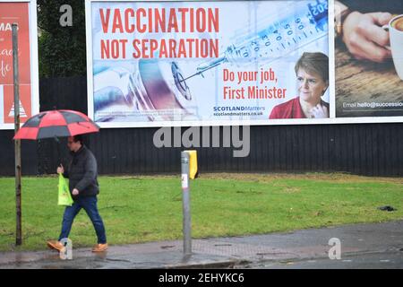Greenock, Scozia, Regno Unito. 20 febbraio 2021. Nella foto: Immagine del primo ministro scozzese Nicola Sturgeon con la grafica di un vaccino COVID19 e una siringa con lo slogan: "VACCINAZIONE NON SEPARAZIONE. FAI IL TUO LAVORO, PRIMO MINISTRO." su un cartellone nel mezzo di Greenock, in un crocevia trafficato di Brougham St & Campbell St. Questo è in riferimento alla maggioranza silenziosa di persone in Scozia che si oppongono alla SNP cercando un secondo referendum sull'indipendenza nel mezzo di una pandemia che lo ha fatto Nel Regno Unito sono state uccise oltre 106,000 persone, di cui 6,816 nella sola Scozia. Credit: Colin Fisher/Alamy Live News. Foto Stock