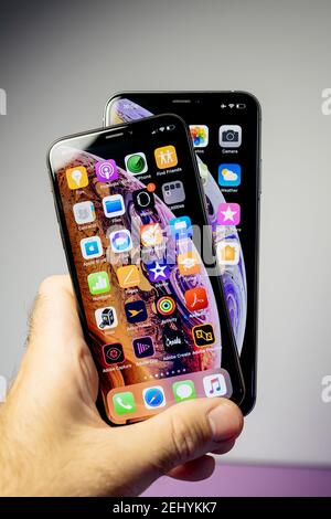 Parigi, Francia- 2 ottobre 2018: POV mano maschile tenendo mostra due ultimi Apple computer iPhone smartphone la versione 11 12 pro in versione max e normale - tutte le applicazioni home sul display oled retina Foto Stock