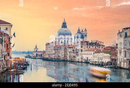 Vista mozzafiato dello skyline di Venezia con il Canal Grande e la Basilica di Santa Maria della Salute in lontananza durante una suggestiva alba. Foto Stock