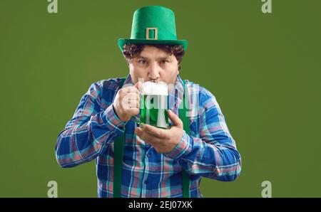 Giovane irlandese in leprechaun party cappello bevendo birra verde Il giorno di San Patrizio Foto Stock