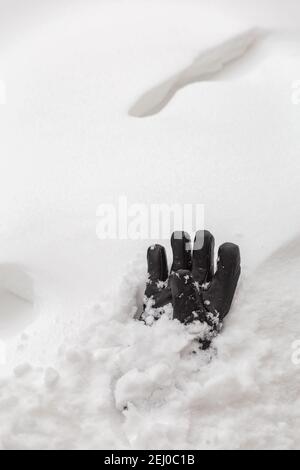 Guanto in pelle nera sulla neve con un footstep in background Foto Stock