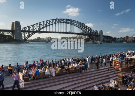 I clienti dell'Opera Bar presso l'Opera House, di fronte al Sydney Harbour Bridge, Sydney, New South Wales, Australia. Foto Stock