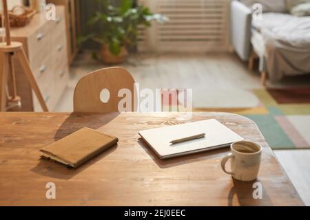 Immagine di sfondo dai toni caldi di un accogliente ufficio domestico con computer portatile su una scrivania di legno illuminata dalla luce del sole, spazio per la copia Foto Stock