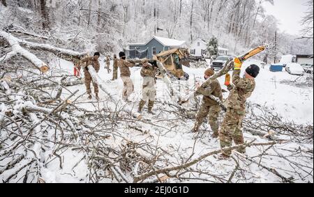 Ceredo, Stati Uniti. 19 Feb 2021. Soldati degli Stati Uniti con la West Virginia National Guard eliminare i detriti da una tempesta invernale fuori di una strada 19 febbraio 2021 a Ceredo, Wayne County, West Virginia. Un grande sistema di tempeste invernali all'inizio della settimana ha lasciato più di 90,000 West Virginia senza elettricità in tutta la regione, abbattendo gli alberi e rendendo le strade remote impassabili. Credit: Planetpix/Alamy Live News Foto Stock