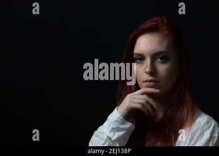Basso ritratto chiave di bella giovane donna con la mano sul mento. Orizzontalmente. Foto Stock