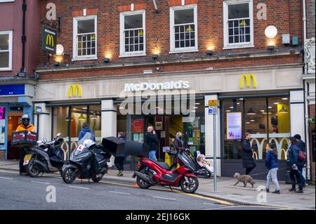 Windsor, Berkshire, Regno Unito. 19 febbraio 2021. Consegna moto autista fila fuori McDonald's. Windsor è stata molto più tranquilla del solito per un semestre scolastico in quanto molte persone seguono i consigli del governo e rimangono a casa durante il Covid-19 Coronavirus National Lockdown. Lunedì 22 febbraio 2021, il primo ministro Boris Johnson presenterà una tabella di marcia su come l'Inghilterra verrà fuori dai blocchi. Credito: Maureen McLean/Alamy Foto Stock