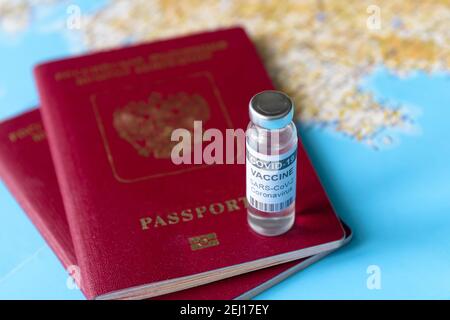 Coronavirus, viaggio e concetto di vaccino, bottiglia di vaccino COVID-19 e passaporti su mappa turistica. Vaccinazione COVID a causa di restrizioni e blocco. Foto Stock