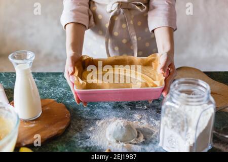 Impasto di torta cruda con banane dimezzate in ceramica a forma rettangolare. Torta alla banana Foto Stock