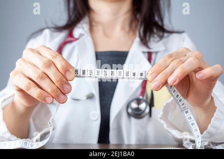 Primo piano immagine isolata di un medico caucasico che tiene un metro a nastro nelle mani che mostra 102 centimetri come addominale limite superiore circonferenza in he Foto Stock