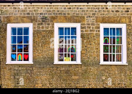 Warminster, Wiltshire UK - Aprile 22 2020: Finestre di una casa decorata con Rainbow di speranza, grazie NHS e Key Workers messaggi Foto Stock