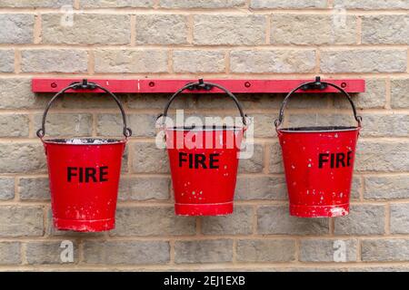 Tre red fire bucket appeso a una parete Foto Stock