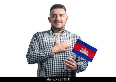 Ragazzo bianco che tiene una bandiera della Cambogia e tiene la mano sul suo cuore isolato su uno sfondo bianco con amore per la Cambogia. Foto Stock