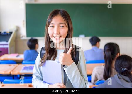 asian cute studentessa adolescente ragazza mostrando pollici in classe Foto Stock