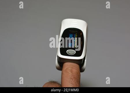 pulsossimetro fingertip collegato al dito indice di un giovane che misura la saturazione di ossigeno nel sangue e nel cuore tasso Foto Stock