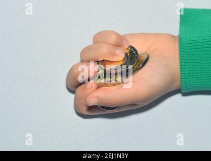 Mano del bambino che contiene alcune monete ,. Concetto di risparmio di denaro . raccolta di denaro egiziano. Foto Stock