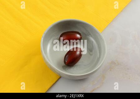 Pezzi di caramella dura frizzante aromatizzati Cola in ciotola con giallo tovagliolo sul tavolo Foto Stock