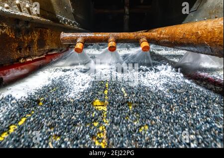 Schermo vibrante, lavaggio con liquido. Il liquido viene versato in un flusso simile a un ventilatore da appositi ugelli Foto Stock