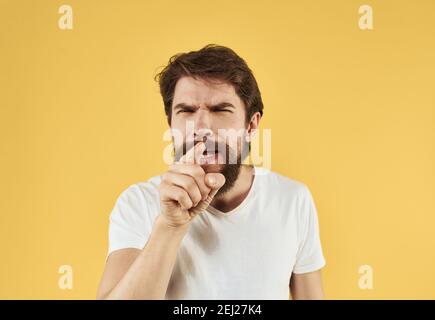 Uomo bearded che tiene le mani vicino al viso su sfondo giallo primo piano vista ritagliata Foto Stock