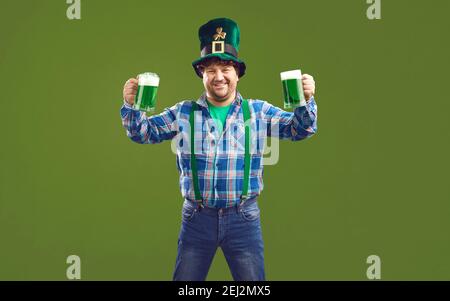 Uomo positivo che tiene tazze di birra verde per Patricks giorno Foto Stock