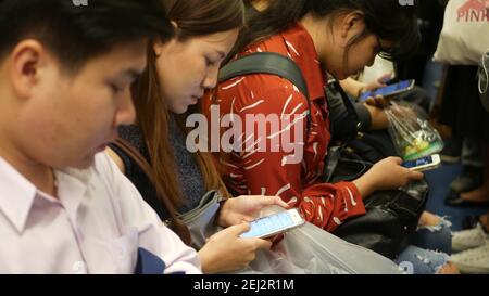 BANGKOK, THAILANDIA - 18 DICEMBRE 2018: Passeggeri alla stazione BTS Skytrain di Bangkok, Thailandia, tutti guardano verso il basso smartphone mentre aspettano t Foto Stock