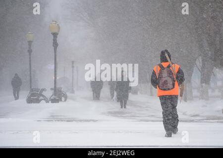 Un uomo che lavora al servizio comunale con una pala da neve cammina lungo la strada in una tempesta, una bizzarda o una nevicata in inverno in caso di maltempo nella città.E. Foto Stock