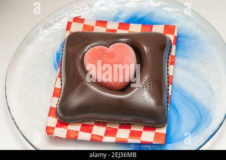 Gelato vegano per la giornata di San Valentino, cioccolato e fragola, forma a cuore, su un piatto di vetro Foto Stock