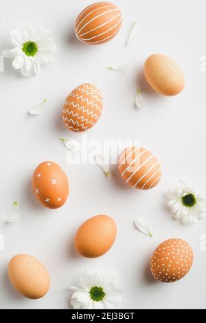 Piatto di Pasqua composizione di posa. Uova di Pasqua e fiori di primavera su sfondo bianco. Disposizione piatta, vista dall'alto, verticale. Foto Stock