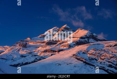 Tramonto invernale sulla vetta del Monte Perdido e sulle cime del Soum de Ramond e Punta de las Olas (Ordesa e Parco Nazionale del Monte Perdido, Pirenei, Spagna) Foto Stock