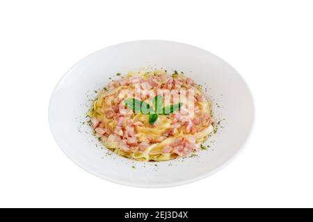 Piatto isolato di pasta carbonara fatto di tagliatelle, pancetta, parmigiano condito con foglie di basilico. Foto Stock