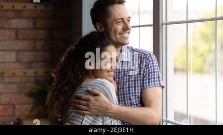 Primo piano sorridente giovane coppia sognante abbracciando, visualizzando il futuro Foto Stock