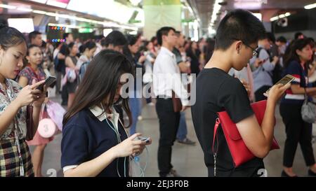 BANGKOK, THAILANDIA - 18 DICEMBRE 2018: Passeggeri alla stazione BTS Skytrain di Bangkok, Thailandia, tutti guardano verso il basso smartphone mentre aspettano t Foto Stock