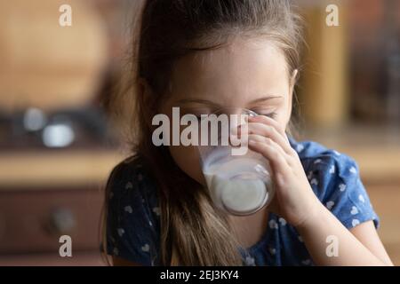 Primo piano cute bambina con occhi chiusi bere latte Foto Stock