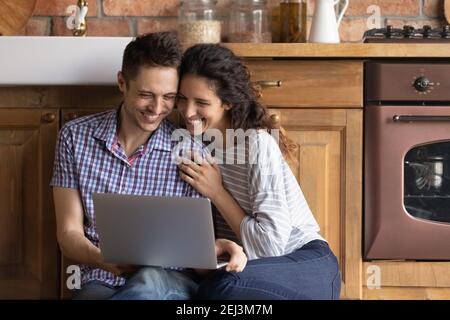 Primo piano giovane coppia felice usando il computer portatile, seduto in cucina Foto Stock