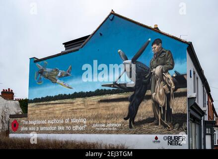 Loughborough, Leicestershire, Regno Unito. 21 febbraio 2021. Un murale sul lato di un edificio a Loughborough raffigura il leggendario Air Vice Marshal James Edgar ‘Johnnie’ Johnson, nato localmente. L'opera rende omaggio al pilota della seconda guerra mondiale RAF Spitfire, meglio conosciuto come Johnnie Johnson, che ha abbattuto più aerei nemici di qualsiasi altro pilota di combattimento alleato durante la guerra, volando circa 700 sorti operativi. Dipinto da Buber Nebz, il murale fa parte del collettivo Ladybird, che si trova dietro diverse opere d'arte che appaiono a Loughborough. Credit: Matt BLimit/Alamy Live News Foto Stock