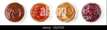 Set di varie salse dolci - crema di cioccolato, marmellata d'arancia, burro di arachidi e marmellata di frutti di bosco misti in un piatto rotondo isolato su sfondo bianco, vista dall'alto Foto Stock