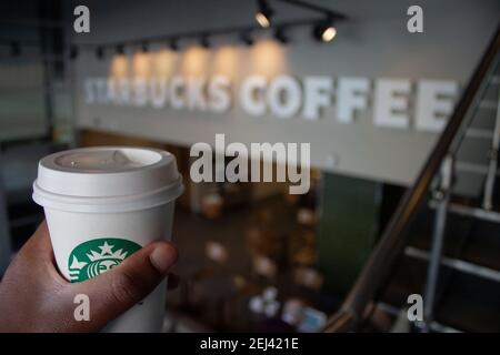 Interno Starbucks cafe. Un uomo nero prende un caffè. Starbucks Corporation è un'azienda di caffè e una catena di caffetterie a livello globale Foto Stock