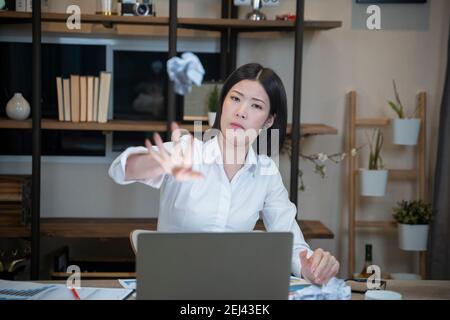 Donna d'affari in ufficio gettando carta sgualcita in carta di spreco. Foto Stock