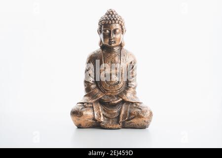 Una statua ricordo al coperto di buddha in bronzo in posizione di loto isolato su uno sfondo bianco e una superficie pianeggiante. Foto Stock