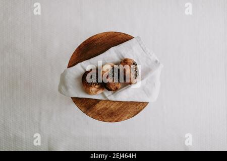 Tre farina di impasto con semi di papavero e sesamo su un tovagliolo su uno sgabello di legno Foto Stock