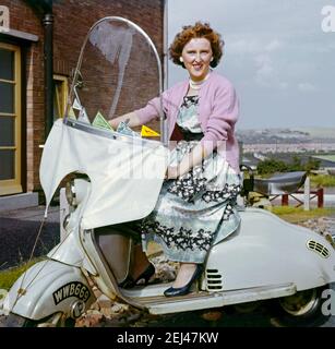 Giovane donna su scooter Lambretta c.1960. I luoghi visitati dallo scooter sono esposti come pennants sul parabrezza - una fotografia d'epoca da poco prima dell'epoca in cui gli scooter sono diventati una forma 'mod' di trasporto con la cultura giovanile britannica. Questa immagine proviene da una vecchia trasparenza di colore amatoriale. Foto Stock