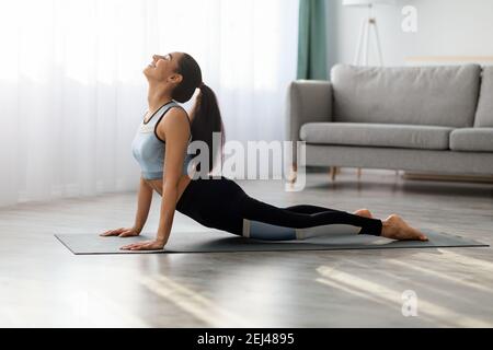 Giovane donna flessibile che pratica yoga a casa Foto Stock