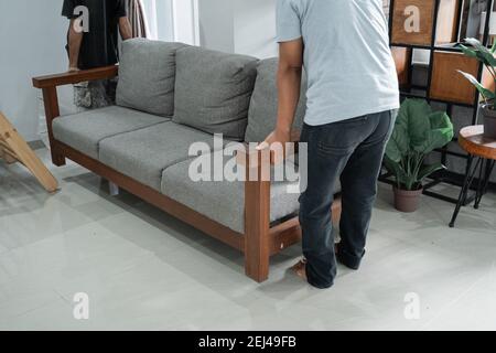 un divano grigio portato da due uomini nel soggiorno. concetto di movimento Foto Stock