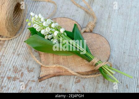 Giglio del valleybouquet (Convallaria majalis) su cuore di legno Foto Stock