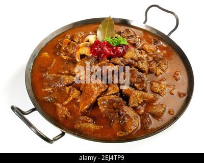 Selvaggina ragù di carne in una padella con mirtilli rossi isolati Su sfondo bianco Foto Stock