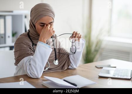 Medico femminile che ha problemi di vista mentre lavora con il computer portatile Foto Stock