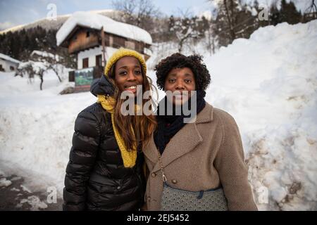 Bel ritratto di una madre nera sorridente e di sua figlia posa per una foto in montagna al freddo con neve Foto Stock