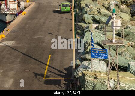 Folegnadros, Grecia - 26 settembre 2020: Vista sul porto dell'isola di Folegandros. Auto verde parcheggiata sulla strada. Frangiflutti lungo la strada. Foto Stock