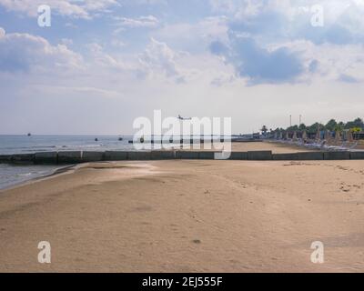 Aereo basso sopra il mare blu mediterraneo con onde e spiaggia di sabbia che vola all'aeroporto di Larnaca, Cipro. Navi all'orizzonte. Foto Stock