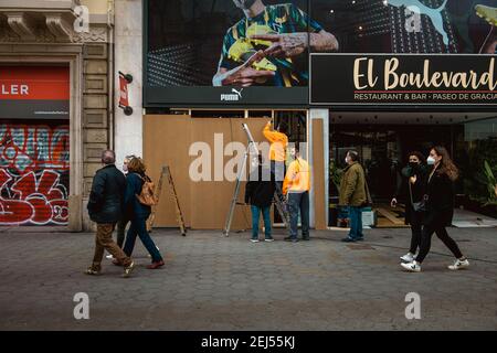 Barcellona, Spagna. 21 Feb 2021. I lavoratori salgono a bordo di un negozio dopo che i sostenitori dell'artista imprigionato Pablo Hasel, accusati di incarcerare per glorificare il terrorismo e insultare l'ex re spagnolo in lyrics, hanno dimostrato in una notte di rivolte e saccheggi. Credit: Matthias Oesterle/Alamy Live News Foto Stock