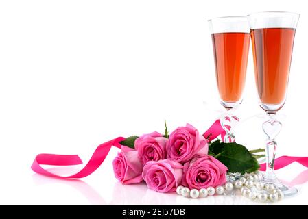Concetto di San Valentino. Due bicchieri di vino, rose rosse e una serie di perle su sfondo bianco con spazio di copia per il testo. Messa a fuoco selettiva. Foto Stock